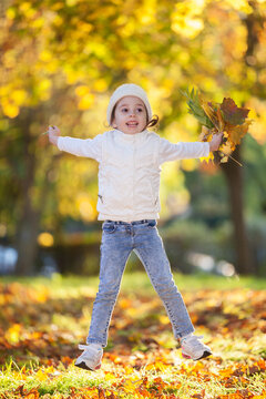 Happy girl playing yellow leaves in the autumn park. Beauty nature scene with family outdoor lifestyle. Happy girl having fun outdoor. Happiness and harmony in childhood