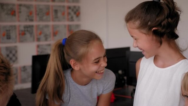 Portrait of happy children at school in the office at a robotics lesson, with a modern office with computers in the background.