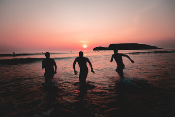 boys running into the sea at sunset