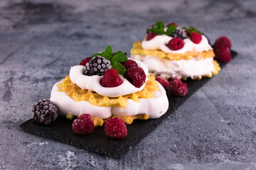 
Waffles with delicate cream and berries on a black slate board.