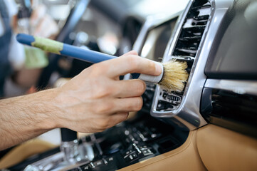 Worker with brush wipes car air duct grating