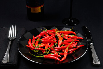 Full plate of red hot Chili Peppers at a black table setting with wine from Chile