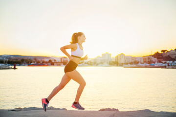 City running - Young teenager girl runner training along the promenade during sunset