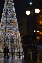 A couple admiring a large Christmas tree in a square in Cadiz, Spain. © juanorihuela