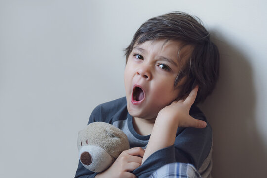 Emotional Kid yawning, Sleepy child siting alone in the coner and looking at camera, Indoor portrait tired boy get a cold during weather change, Children health care concept