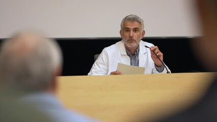 Doctor giving conference in convention center, audience in rear view
