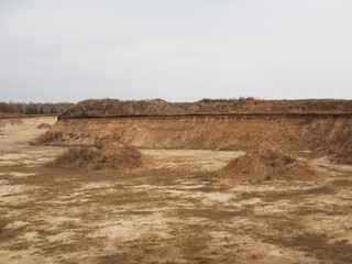 A large hills and pits of sand and traces of a heavy bulldozer and tractors on a autumn forest construction site. Panoramic collage from several outdoor sunny October day shots