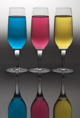 Set of glasses filled with water with different colors on table in photo studio.