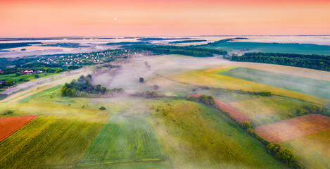 Colorful dawn on Ukrainian countryside with foggy fields. Amazing summer sunrise on outskirts of...