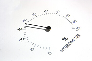 Closeup of the needles of an analog hygrometer on white