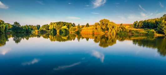 Calm morning scene of small pond in the outskirts of Ternopil town, West Ukraine, Europe. Panoramic summer view of Ukrainian countryside. Beauty of nature concept background..