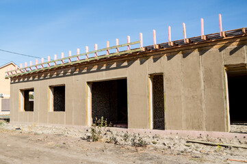 Obraz premium Construction of a house from an environmentally friendly material of plant origin. Frame made of wood, blocks of straw, clay plaster.