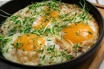 scrambled eggs with greens sprouts and green onions in a pan
