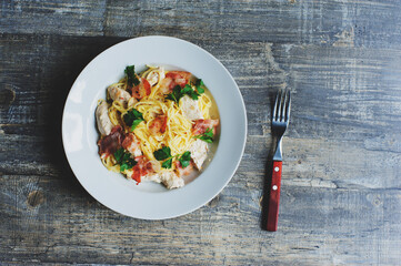 top view of cooked creamy cheese pasta with roasted chicken and bacon served on plate for one person