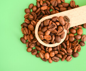 Coffee beans in a wooden spoon isolated on a light background. Сoffee beans are scattered. Selective macro focus.