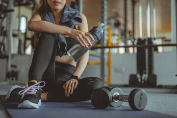 Woman exercise workout in gym fitness breaking relax after training sport with dumbbell and holdingbottle, Athlete lifestyle. Fitness ,workout, gym exercise,lifestyle and healthy concept.
