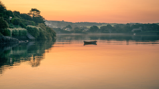 Camel estuary at dawn with sunrise reflected on the calm water with boats at moorings.
