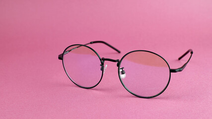 Round eyeglasses on a pink background. Fashionable round computer glasses