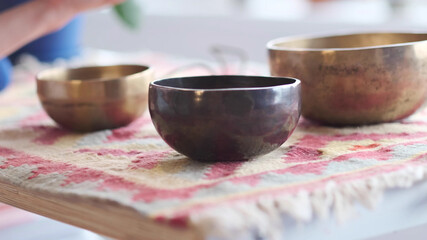 Woman playing on Tibetan singing bowl while sitting on yoga mat. Vintage tonned.