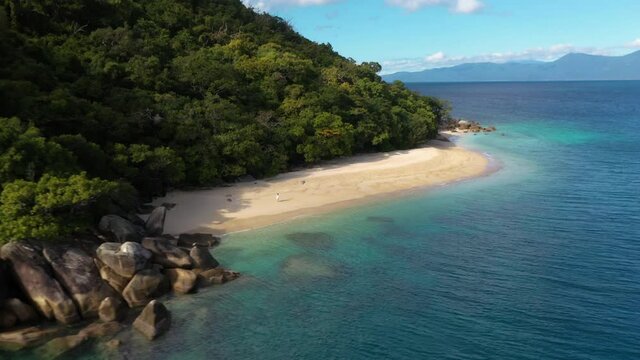 Wide rotating drone shot of woman walking on Nudey Beach on Fitzroy Island
