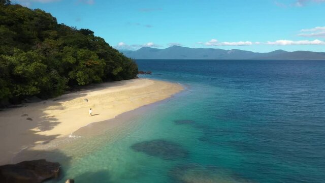 Wide rotating drone shot of woman walking on Nudey Beach on Fitzroy Island