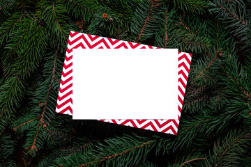Fototapeta na wymiar Christmas tree branches with paper card note. Nature New Year concept. Merry Christmas card, background. Congratulations, holidays, celebration. Mock up, copy space, flat lay. Red, green and white.