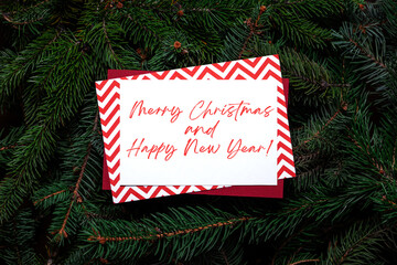 Christmas tree branches with paper wishing card note. Nature concept. Merry Christmas Happy New Year card, background. Congratulations, holidays, celebration. Red, green and white. Ready to use, print