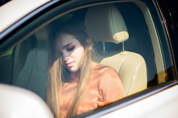 Close up portrait of pleasant looking female girl with, sits on driver`s seat, enjoys music. People, driving, transport concept.Portrait of beautiful young woman in the new car - outdoors