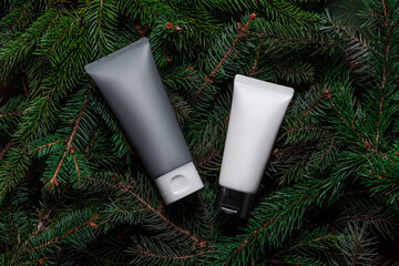 White, grey tubes, bottles of cream or body lotion on green branches background. Two. Pine, fir, spruce. Organic cosmetic. Treatment spa beauty skincare healthcare Brand commercial Product Top view