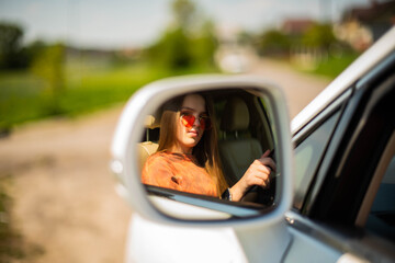 Close up portrait of pleasant looking female girl with, sits on driver`s seat, enjoys music. People, driving, transport concept.Portrait of beautiful young woman in the new car - outdoors