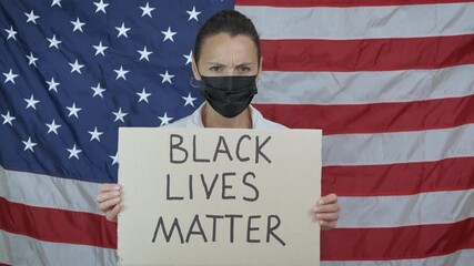 Supports black movement. A sad woman in protective mask support an anti racism movement and hold a cardboard with a slogan black lives matter.