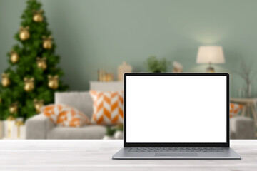 Blank display screen laptop computer on white wood table. Modern cozy comfortable home living room with Christmas decor. Home office desk workspace. Mock up copy space. Winter sales, online shopping