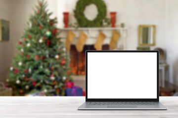 Blank display screen laptop computer on white wood table. Modern cozy comfortable home living room with Christmas decor. Home office desk workspace. Mock up copy space. Winter sales, online shopping
