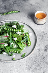 Healthy sweet pea salad with greens and red dressing food photography