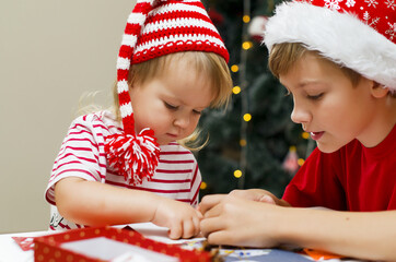 Brother and sister in santa hat making decorations for christmas . Concept of winter kids creativity and christmas craft. Christmas home time