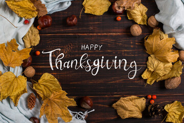 Thanksgiving greetings. Dry leaves, nuts and spices on a dark background, top view. Kaligraphic capital inscription.
