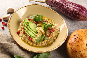 Oriental cuisine. Baba ghanoush. Appetizer of eggplant and chickpeas, seasoned with fresh lemon, olive oil and spices in the bowl on grey table. Tandoor bread. Restaurant menu. Background image