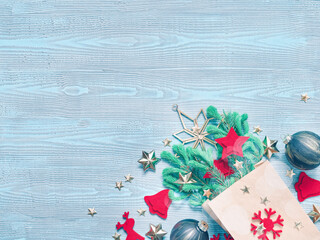 Christmas composition. Natural coniferous branches are in a paper bag. Nearby are red felt decorations, glass balls and golden stars. Blue wooden background. Flat lay, top view, copy space