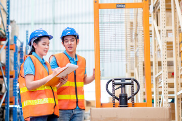 Warehouse man and woman or factory workers discuss together about checking stock of products and...