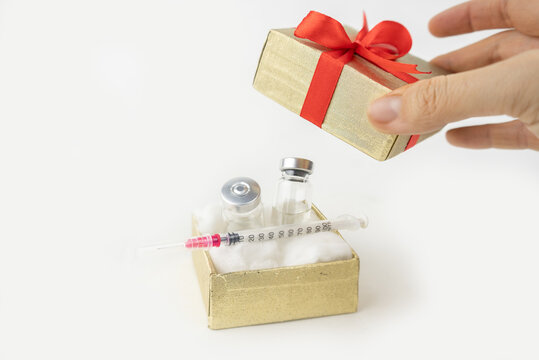 Best gift for holiday or birthday in 2021 is covid-19 vaccine. Vaccine bottle and syringe in a present box