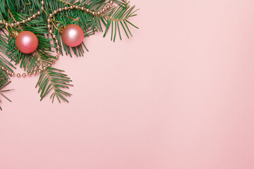 Christmas pink background with fir branch, pink balls and beads in the corner with copy space. 