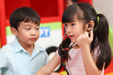 Adorable kid pretending to be doctor, playing funny and holding doctor stethoscope, pretending...