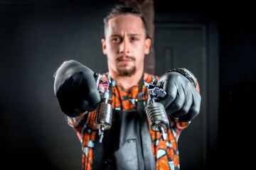 Professional tattoo artist with a tattoo gun in his salon