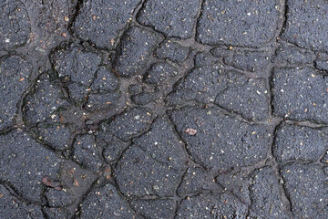 Obraz premium Dark texture of cracked asphalt, broken road surface.