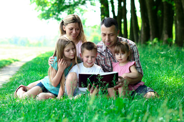 Fototapeta premium young family reading the Bible in nature