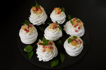 dessert called Anna Pavlova. Meringue with cream garnished with pomegranate, tangerine slices and Basil leaves