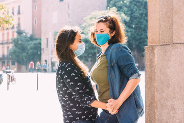 couple of women with a face mask hugging in the street