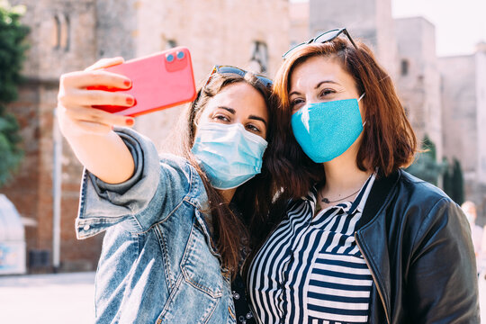 couple of women with a face mask having fun in city taking selfie