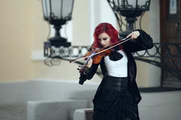 red haired vampire girl plays the violin in an old Museum in Gothic black clothes and a tailcoat © Валерия Старовойтова