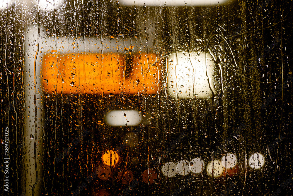 Wall mural close-up and night view of raining water drop on clear transparent glass and defocus background and 
